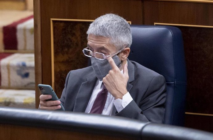 El ministro de Interior, Fernando Grande-Marlaska, observa su teléfono móvil en una sesión plenaria en el Congreso de los Diputados.