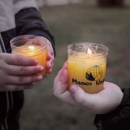 Unos niños sujetan unas velas de Manos Unidas