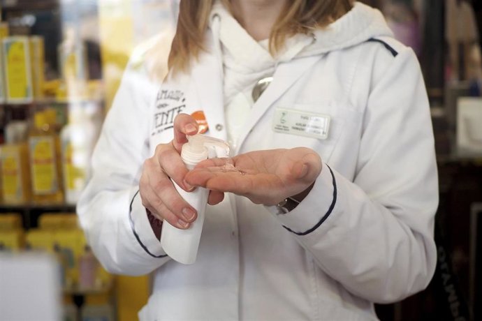 Archivo - Una farmacéutica se echa gel en las manos en una farmacia de Vitoria