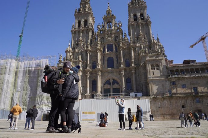 Archivo - Una pareja de peregrinos se echan una foto en la Catedral de Santiago.