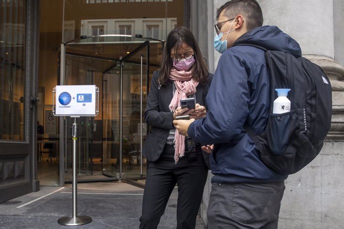 15 October 2021, Belgium, Brussels: People use their mobile phones to run the 'Covid Safe Ticket' app, at the Royal Museums of Fine Arts of Belgium. In Brussels, a Covid Safe Ticket is necessary to enter restaurants, bars, cinemas and fitness centers. P