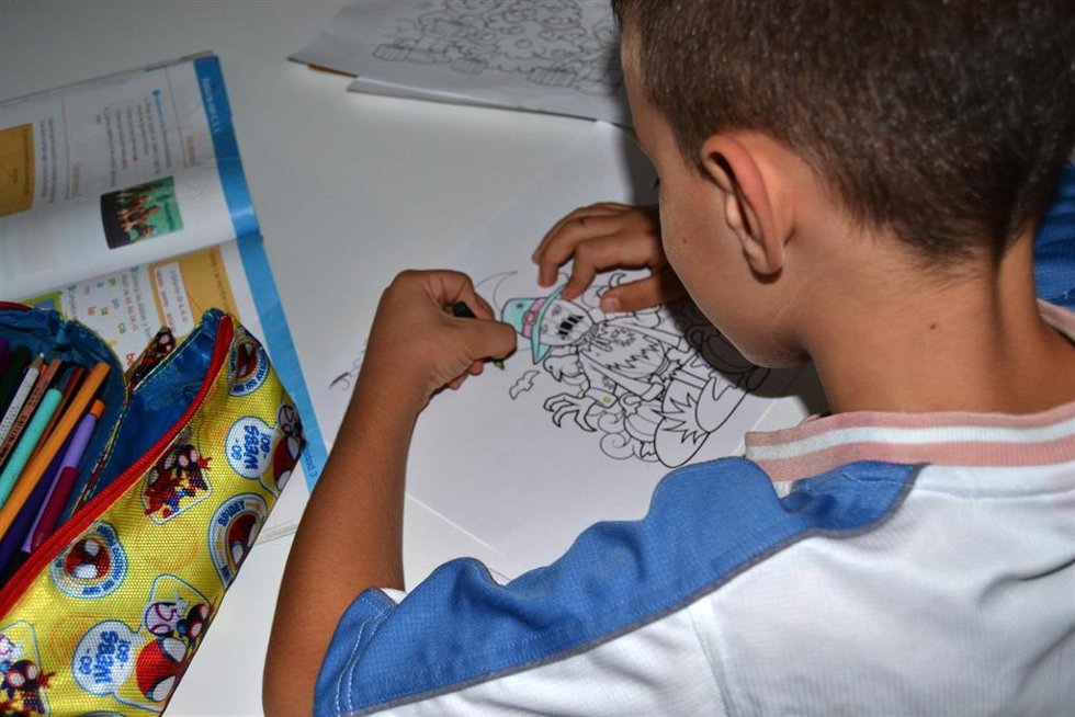 Un menor dibuja en una de las viviendas aportadas por Cáritas Diocesana para familias con necesidades