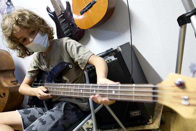 Archivo - Un niño tocando la guitarra en un campamento urbano artístico de teatro musical en Madrid