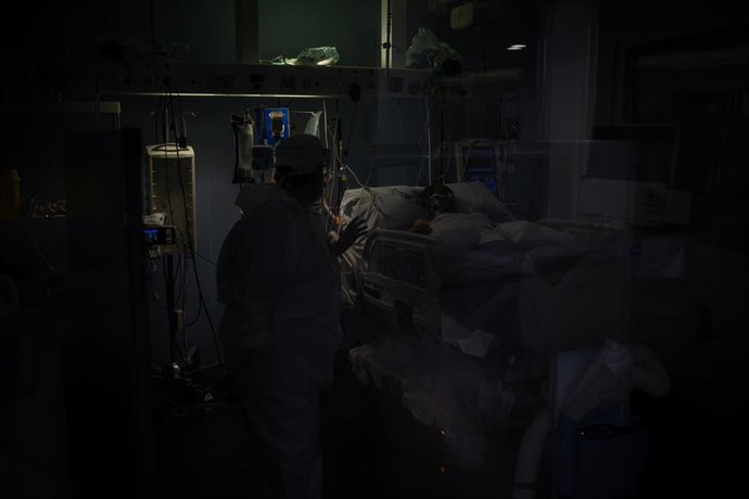 Archivo - Trabajadores sanitarios protegidos atienden a un paciente en una UCI