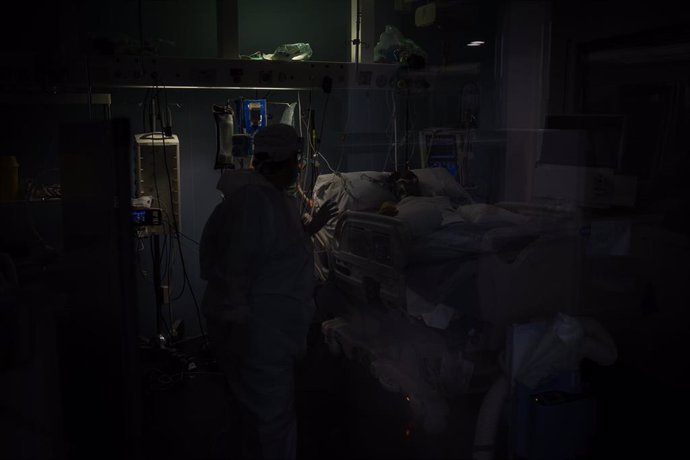 Archivo - Trabajadores sanitarios protegidos atienden a un paciente en una UCI