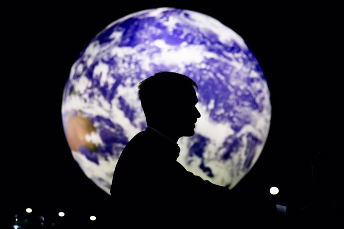 11 November 2021, United Kingdom, Glasgow: A man sits in front of a glowing globe at the UN Climate Change Conference COP26. Photo: Christoph Soeder/dpa