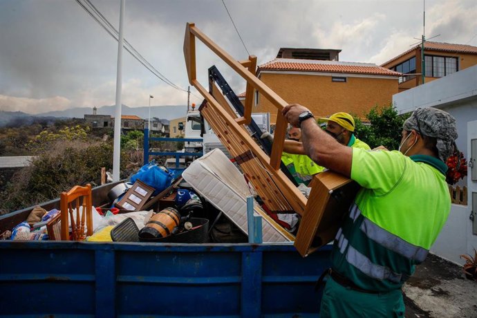 Archivo - Dos hombres de mantenimiento del Ayuntamiento colaboran en recoger las pertenencias de los vecinos del núcleo urbano de Todoque durante el desalojo de sus viviendas 