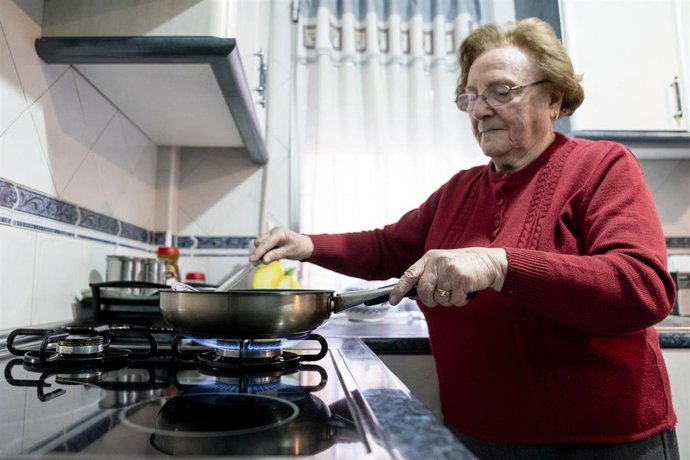 Una mujer prepara comida sobre un fuego de cocina de gas butano
