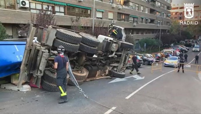 Bomberos del Ayuntamiento de Madrid trabajan en el vuelco de un caminón contenedor de escombros