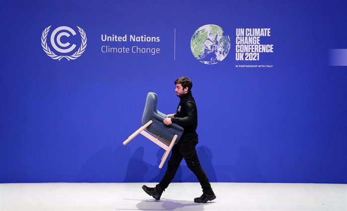 13 November 2021, United Kingdom, Glasgow: A worker removes a chair during the dismantling of one of the stages during the Cop26 summit. Photo: Jane Barlow/PA Wire/dpa