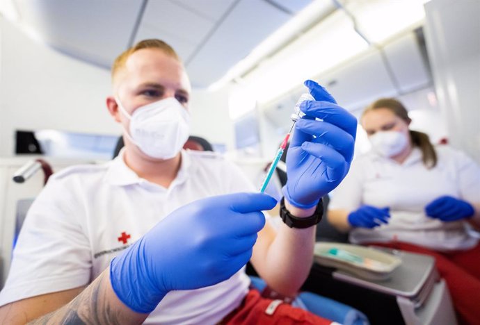 13 November 2021, Austria, Schwechat: A medic prepares a booster jab against coronavirus inside a Boeing 777 aircraft on the tarmac at Vienna International Airport during a vaccination campaign designed by the Vienna International Airport and the Red Cr