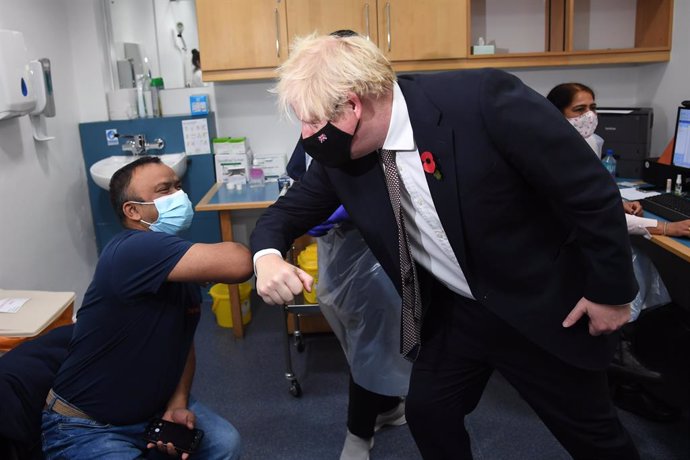 15 November 2021, United Kingdom, London: UKPrime Minister Boris Johnson greets Arzou Miah, who received his booster jab on Monday, during his visit to Woodgrange GP Surgery vaccination centre in east London to meet staff and see people receiving their