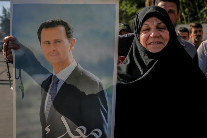 Archivo - Una mujer exhibe una imagen de Bashar al Assad