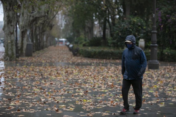 Archivo - La lluvia y el viento ha sido la protagonista en el día de hoy en Sevilla, en la imagen, una persona camina protegido de la lluvia con un chubasquero. En Sevilla, a 20 de enero del 2021.