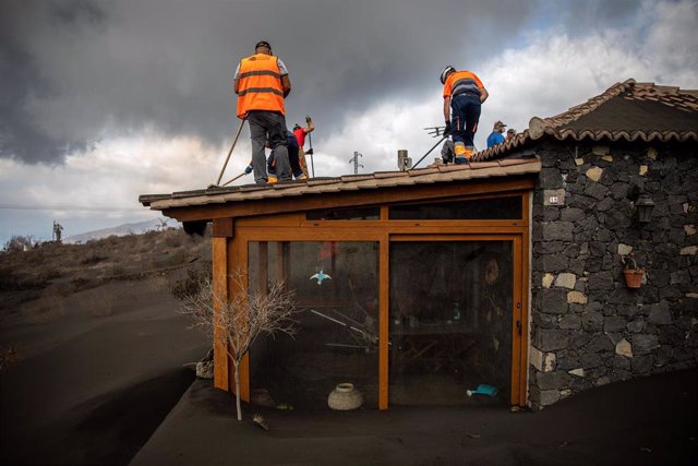 Several volunteers work to remove ashes from the roofs of several houses near the Cumbre Vieja volcano, on November 5, 2021, in La Palma, Canary Islands (Spain).  These volunteers remove from the roofs of the houses and their surroundings the meters d