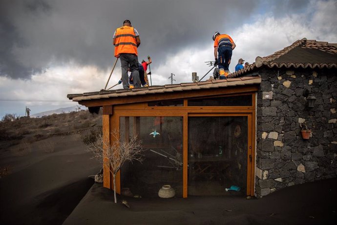 Varios voluntarios trabajan retirando cenizas de los tejados de varias casas próximas al volcán de Cumbre Vieja, a 5 de noviembre de 2021, en La Palma, Canarias (España). Estos voluntarios retiran de los tejados de las casas y sus alrededores los metros