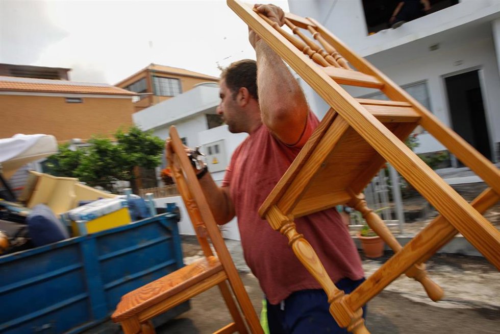 Archivo - Una hombre del núcleo urbano de Todoque recoge sus sillas durante el desalojo de su vivienda ante la aproximación de la lava del volcán