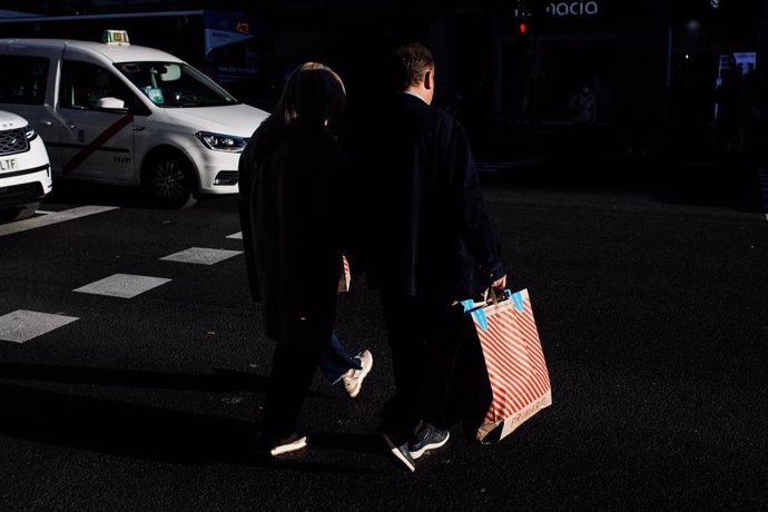 Varias personas caminan con bolsas de compras 