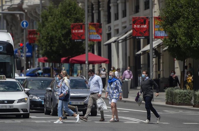 Archivo - Varias personas con mascarillas, cruzan un paso para peatones de Gran Vía