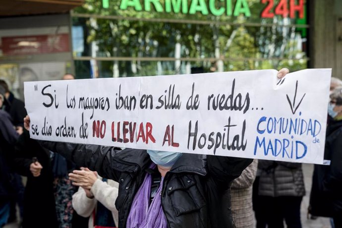 Una mujer sostiene una pancarta donde se lee "Si los mayores iban en silla de ruedas... se dio la orden de no llevar al hospital", durante una concentración frente a la Asamblea de Madrid