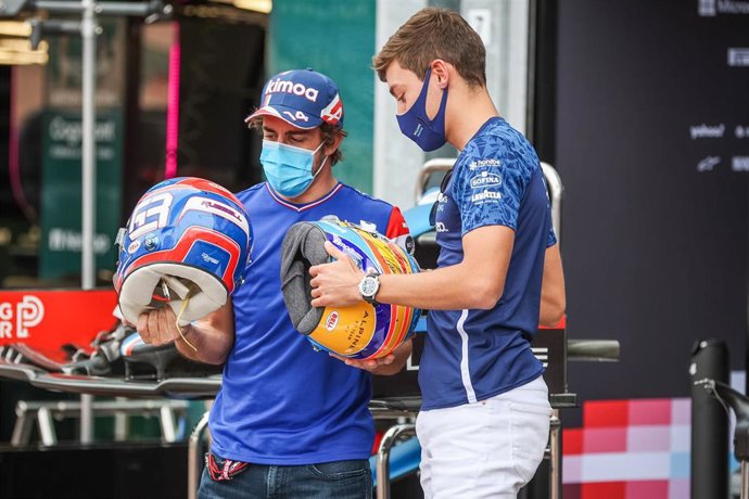 Archivo - Fernando Alonso intercambia su casco con George Russell