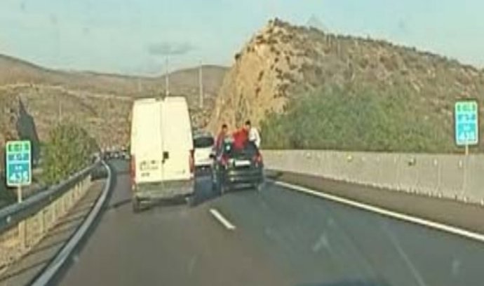 Dos menores viajan subidos a la ventanilla de la parte trasera de un coche en la A-7, en Almería.