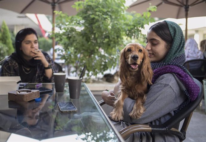Dos mujeres con un perro en una cafetería de Teherán