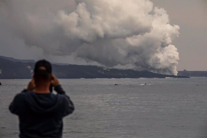 Una persona fotografía una columna de gases de la tercera colada que llega al mar desde el puerto Tazacorte, a 16 de noviembre de 2021, en La Palma, Santa Cruz de Tenerife, Canarias, (España). La erupción fisural del volcán de la isla de La Palma contin