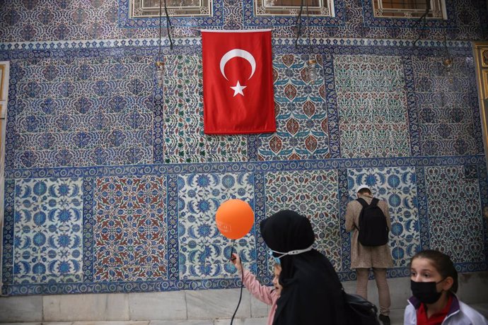 09 November 2021, Turkey, Istanbul: A man prays in front of the tomb of Abu Ayyub al-Ansari in the Eyup district of Istanbul, while a little girl walks by with a balloon in her hands. Photo: Hakan Akgun/SOPA Images via ZUMA Press Wire/dpa