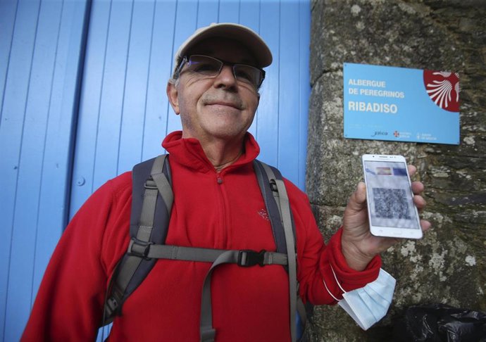 Un peregrino muestra su certificado de vacunación frente a un albergue