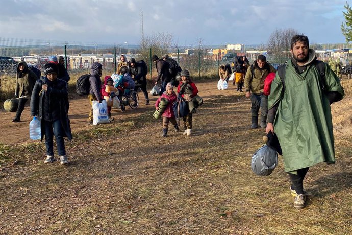 18 November 2021, Belarus, Brusgi: Migrants walk with their luggage in front of the closed border crossing between Belarus and Poland. Around 900 migrants on the border with Poland have spent the night from Wednesday to Thursday outdoors for the 11th co