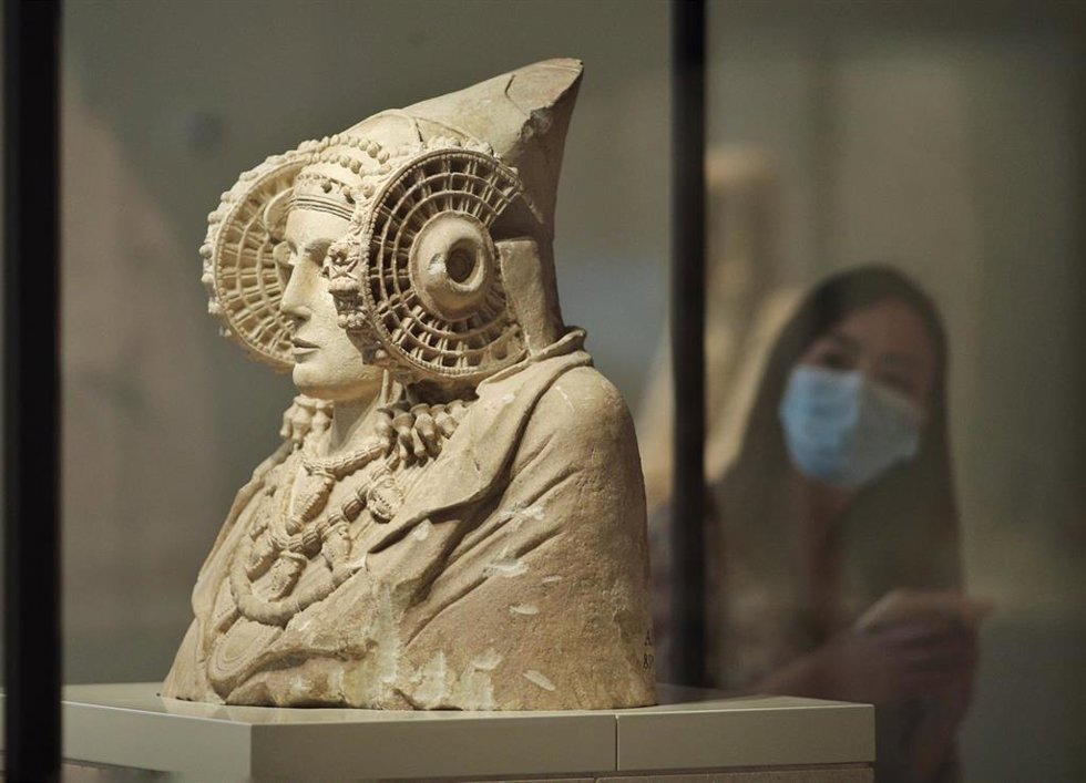 Archivo - Una persona protegida con mascarilla observa la escultura de La Dama de Elche 