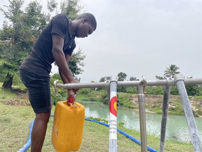 Archivo - Un hombre en un punto de aprovisionamiento de agua instalado con ayuda de AECID en Haití