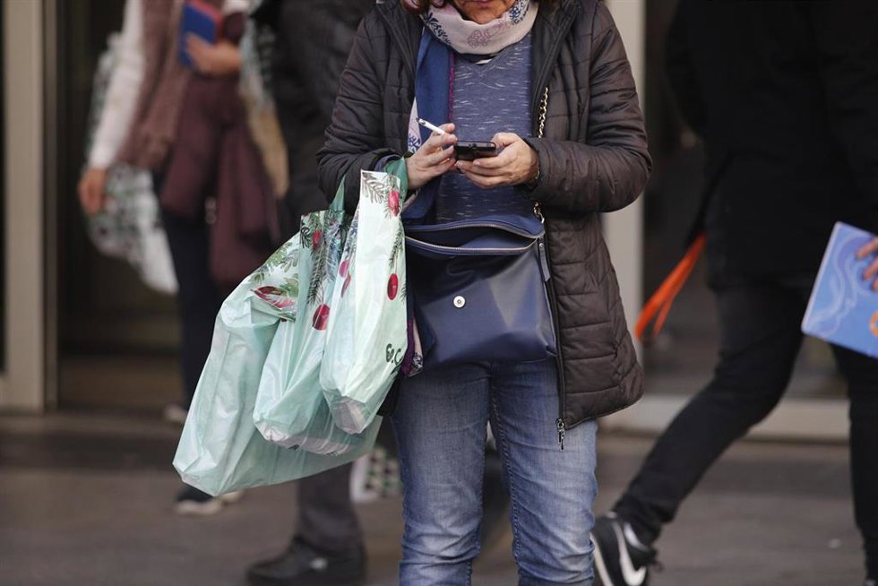 Archivo - Varias personas cargan con bolsas de establecimientos comerciales