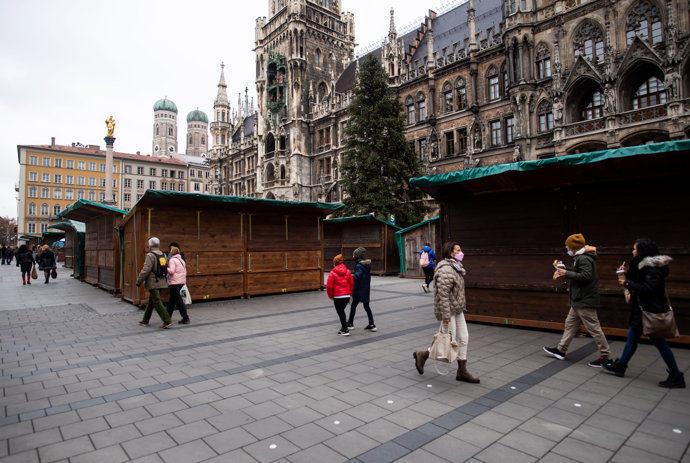 Personas caminando por Marienplatz ante las casetas cerradas del mercado de navidad cancelado, el 20 de noviembre de 2021, en Múnich (Alemania)