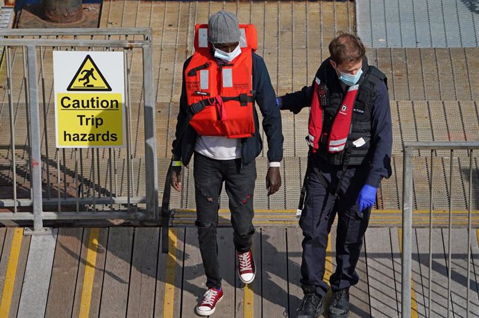 Archivo - 13 September 2021, United Kingdom, Dover: A British border force officer escorts a man as a group of people thought to be migrants are brought into Dover, by a Border Force patrol boat, following a small boat incident in the English Channel. P