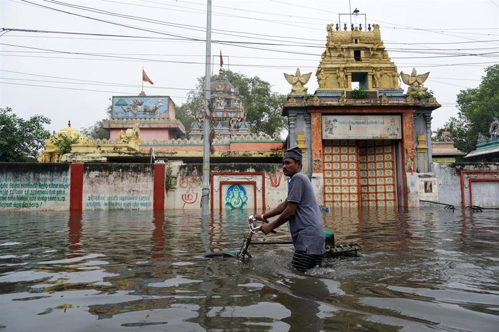 Un hombre cruza una calle anegada por las fuertes lluvias en la región de Chennai, en el sur de India.