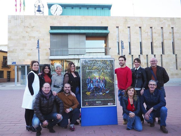 Archivo - El equipo de organización del calendario posa junto al cartel de presentación en la Plaza Mayor de Pedrajas.