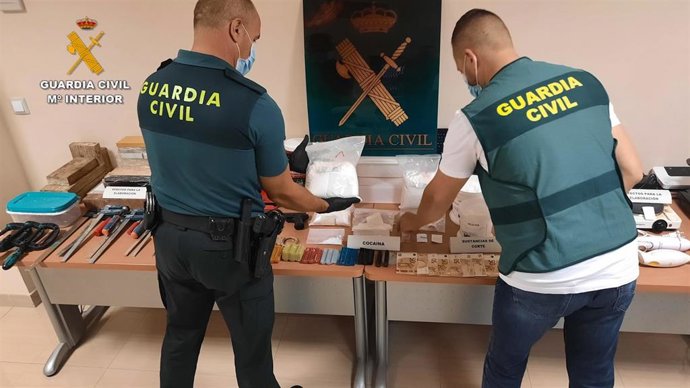 Dos agentes de la Guardia Civil junto a la cocaína y objetos incautados.