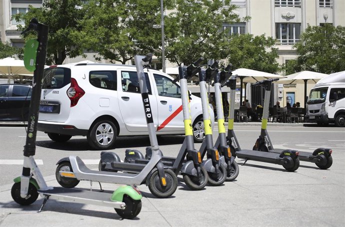 Archivo - Varios patinetes estacionados en una calle céntrica de Madrid.