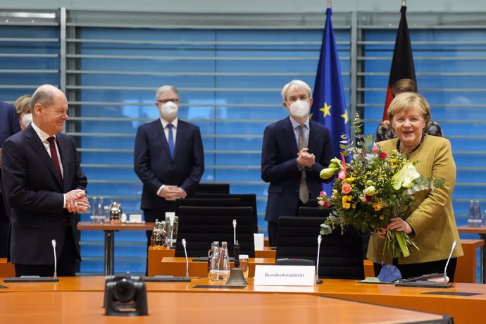 24 November 2021, Berlin: German Chancellor Angela Merkel (R) receives a bouquet from Vice-Chancellor and Finance Minister Olaf Scholz (L)before the cabinet meeting at the Chancellery. Merkel was presented with flowers as this is likely to be her last 