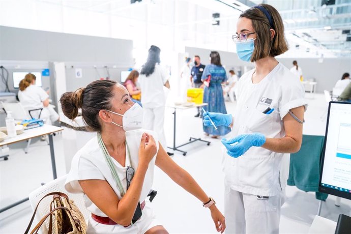 Archivo - Una enfermera conversa con una mujer tras ponerle una vacuna