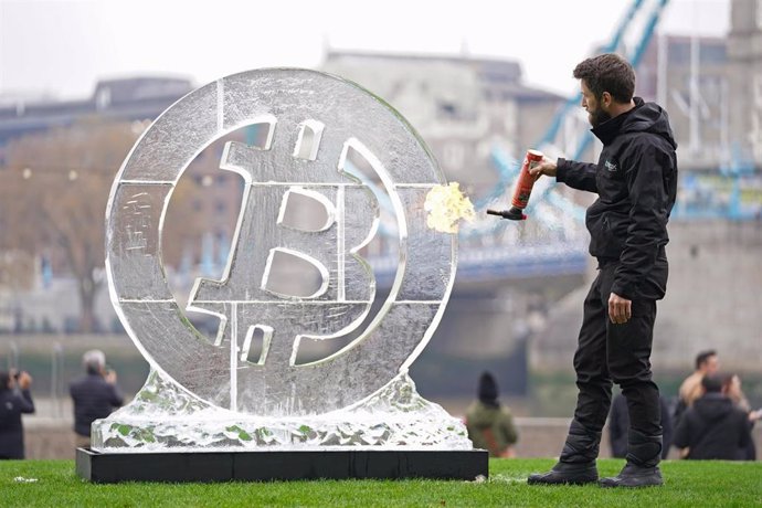 24 November 2021, United Kingdom, London: Ice Sculptor Csaba Vass puts the finishing touches on a large Bitcoin ice carving in front of Tower Bridge to celebrate the eighth anniversary of the world's leading crypto exchange, Huobi Global. Photo: Kirsty 