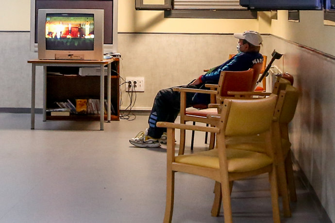 Un señor ve la de televisión en una sala dispuesta para sintecho en el centro Pinar de San José, uno de los centros habilitados por el SAMUR Social para la Campaña del Frío 