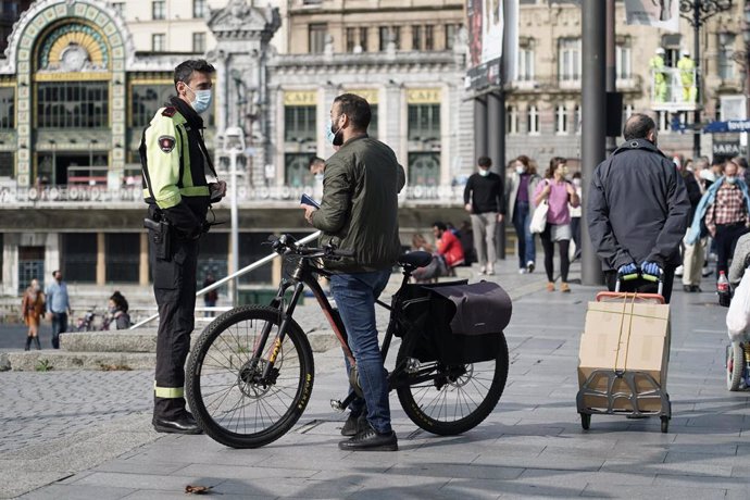 Archivo - Un hombre habla con un agente de la Policía Municipal en Bilbao