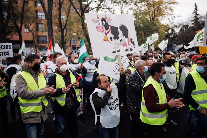 Un grupo de personas participa con pancartas en una concentración de ganaderos del sector lácteo, a las puertas de la sede de la multinacional francesa Lactalis