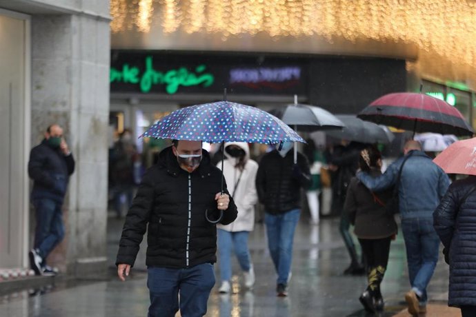 Archivo - Transeúntes pasean protegidos con paraguas