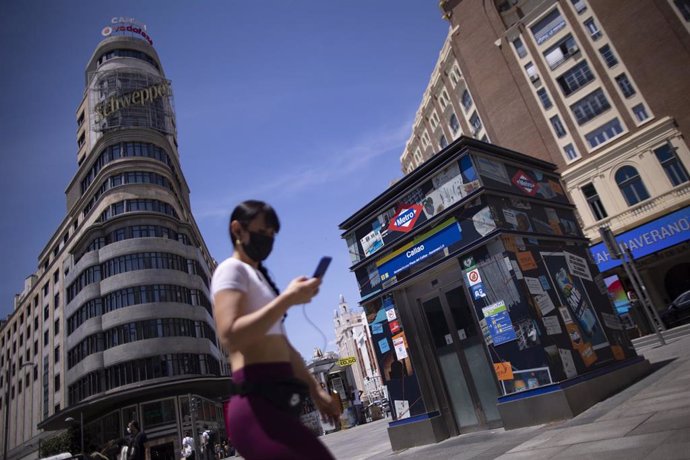 Archivo - Una mujer camina con mascarilla en la Gran Vía de Madrid