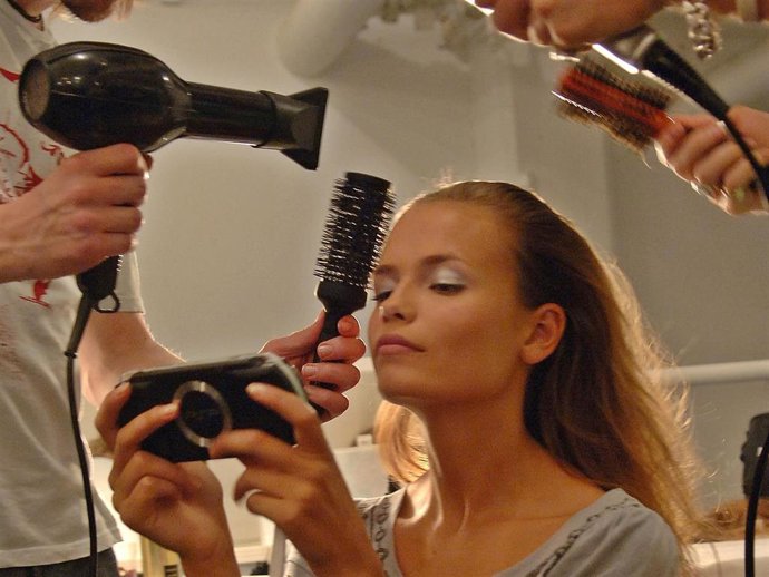Archivo - A model has her hair done while playing a portable video game backstage at the Narciso Rodriguez Spring