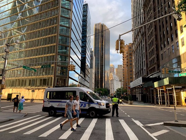 Archivo - 07 June 2020, US, New York: People walk in front of a police vehicle at an almost empty street after the Mayor of New York City Bill de Blasio has lifted the city curfew amid the spread of the coronavirus a day before its original ending day. Ph